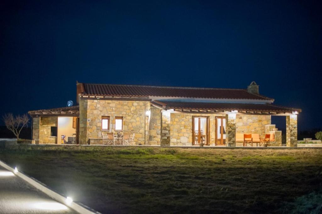 una casa de piedra por la noche con luces encendidas en Villa Marina Limnos en Pedhinón