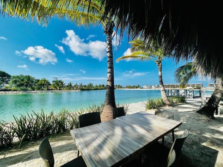 una mesa de madera y sillas en una playa con palmeras en Gadie Villa, en Punta Cana