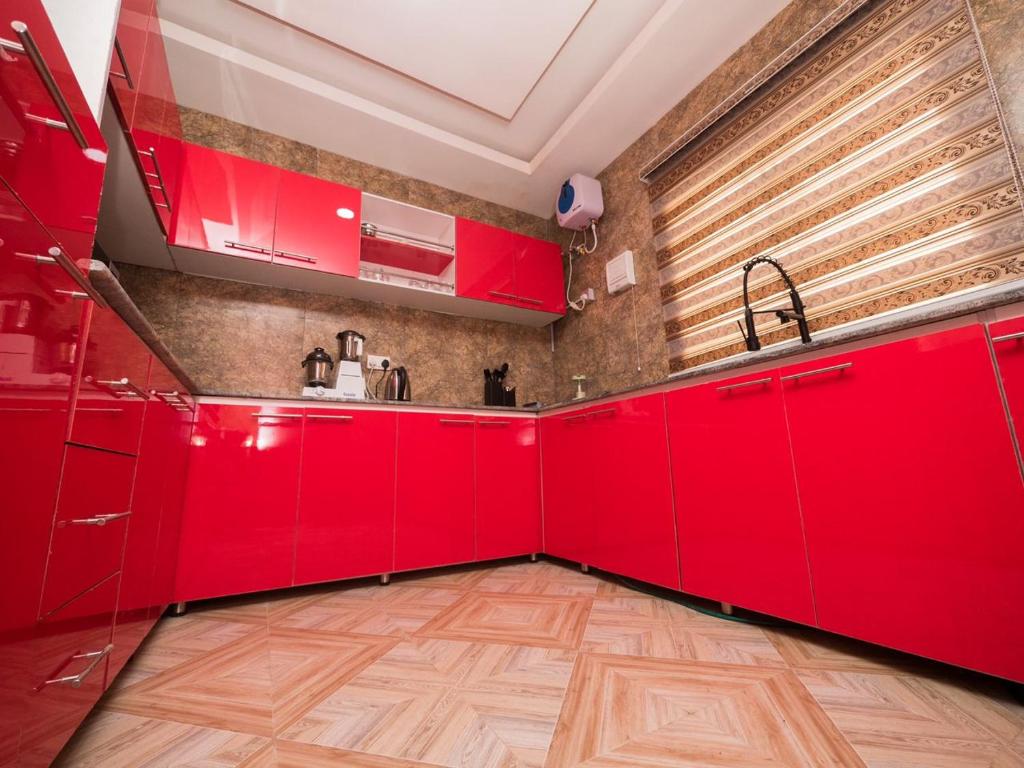 een rode keuken met rode kasten en een houten vloer bij DULCE HOMES 2 BEDROOM FURNISHED SHORT LET in Abeokuta