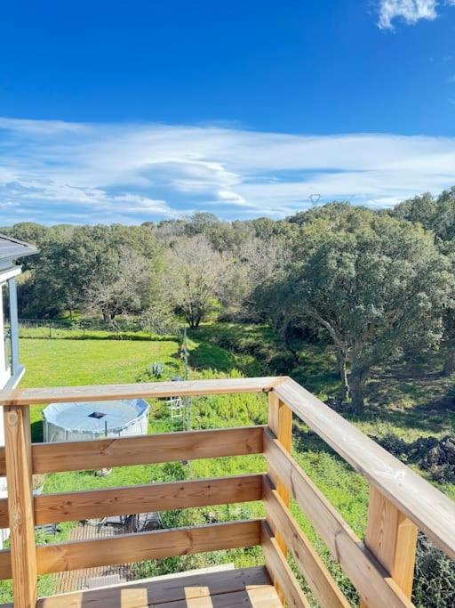 - un balcon en bois avec vue sur un champ et des arbres dans l'établissement Appartement neuf bas de villa 1, à Furiani