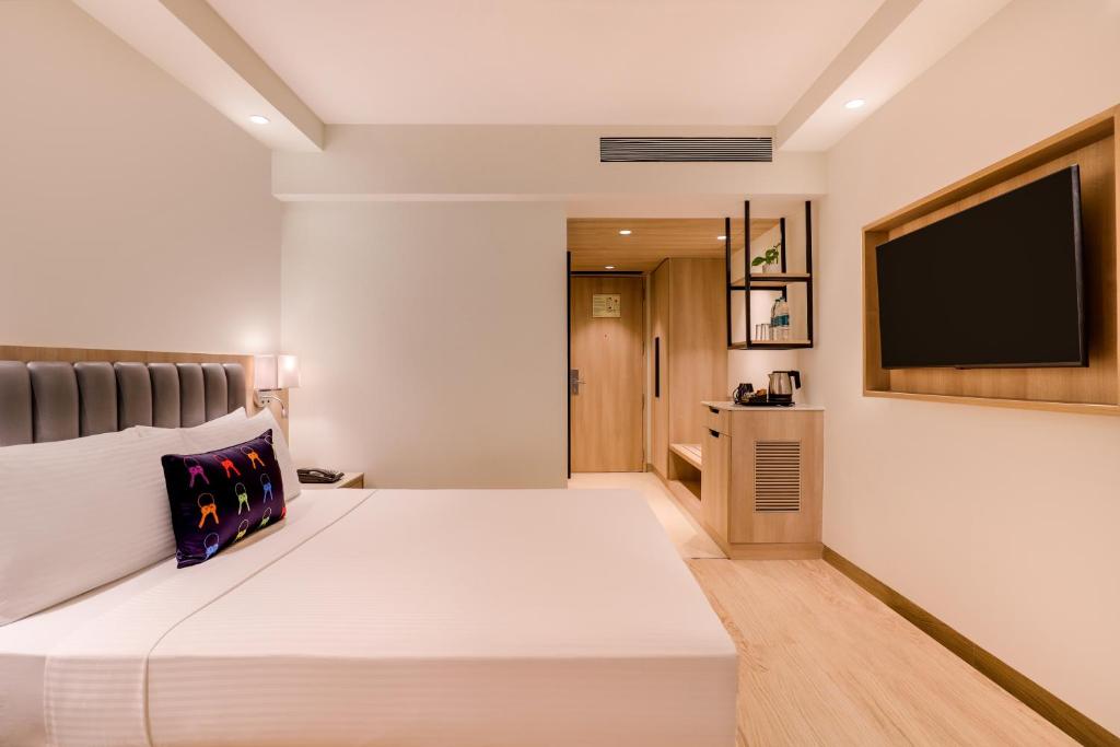 a hotel room with a bed and a flat screen tv at Keys Select by Lemon Tree Hotels, Pimpri, Pune in Pune