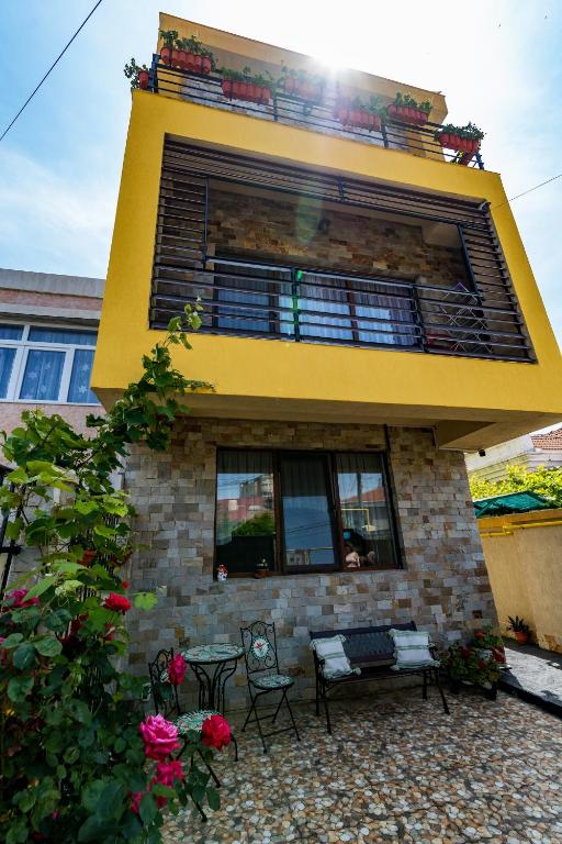 a yellow building with a balcony and a table and chairs at Casa Amelie Mangalia in Mangalia
