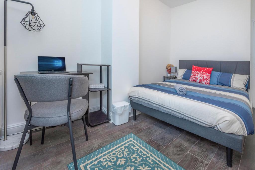 1 dormitorio con cama, silla y ordenador portátil en Modern family home w/Wi-Fi, Netflix, self check-in, en Londres