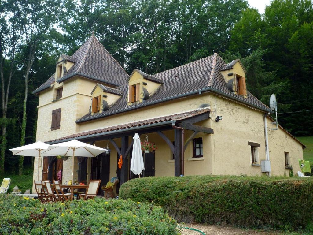 une maison dotée d'un toit avec des tables et des parasols dans l'établissement Les 10 Clés de Montfort/Piscine, à Vitrac