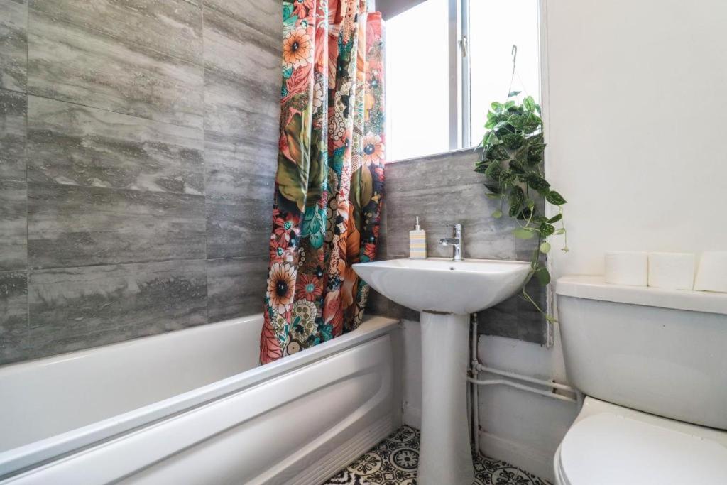 a bathroom with a sink and a shower curtain at Urban Oasis in London