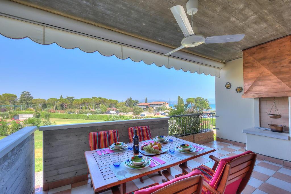 taras ze stołem i krzesłami na balkonie w obiekcie VistaLago Green Residence 100m From Lake - Happy Rentals w mieście Desenzano del Garda
