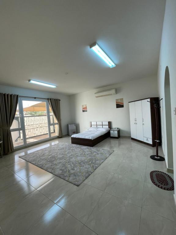 Habitación grande con cama y ventana grande. en للإيجار استوديوهات ضمن فيلا جديده كلياً, en Al Khawḑ