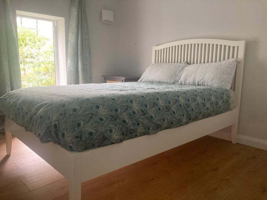 een slaapkamer met een bed met een blauwe deken en een raam bij Bijou Mews in the Victorian Q in Cork