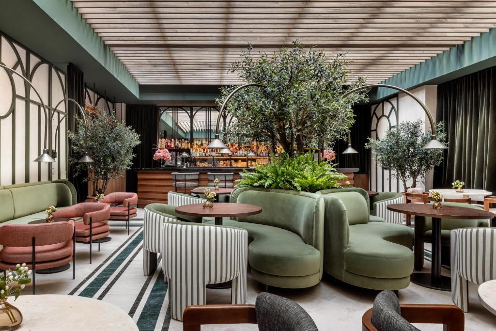 restauracja ze stołami, krzesłami i roślinami w obiekcie TÓTEM Madrid, a Small Luxury Hotel of the World w Madrycie