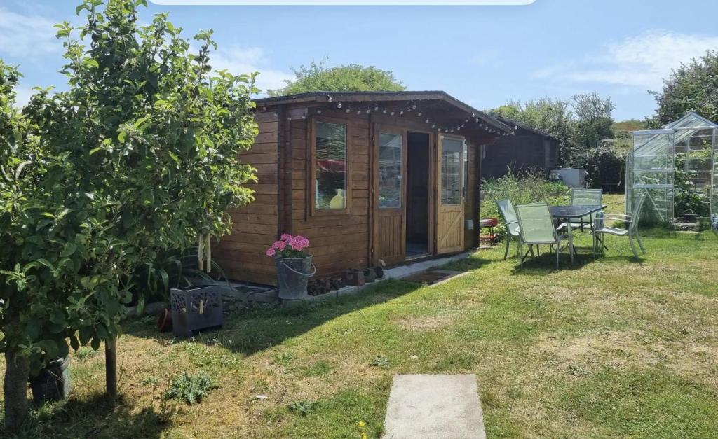 a wooden shed in a garden with a table and chairs at Glamping Cabin - Great for Hikers - Breakfast inc! in Swanage
