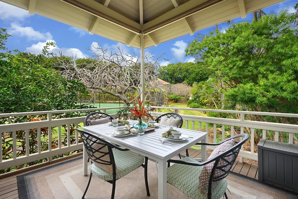 einem weißen Tisch mit Stühlen und einem Sonnenschirm auf der Veranda in der Unterkunft Kauai Birdsong At Poipu Crater in Koloa