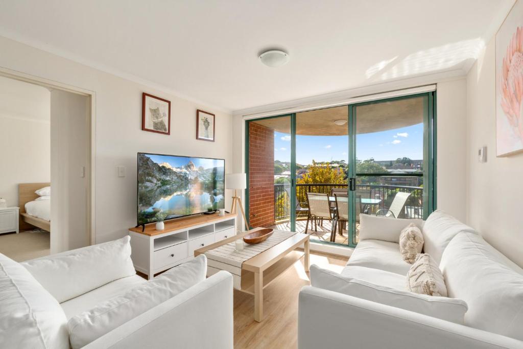 a living room with white furniture and a large window at Spacious 3-Bed with Alfresco Dining by Amenities in Sydney