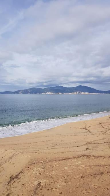 une plage avec l'océan et les montagnes en arrière-plan dans l'établissement T1 bis climatimatisé -Agosta Plage- 10 min à pied, à Albitreccia