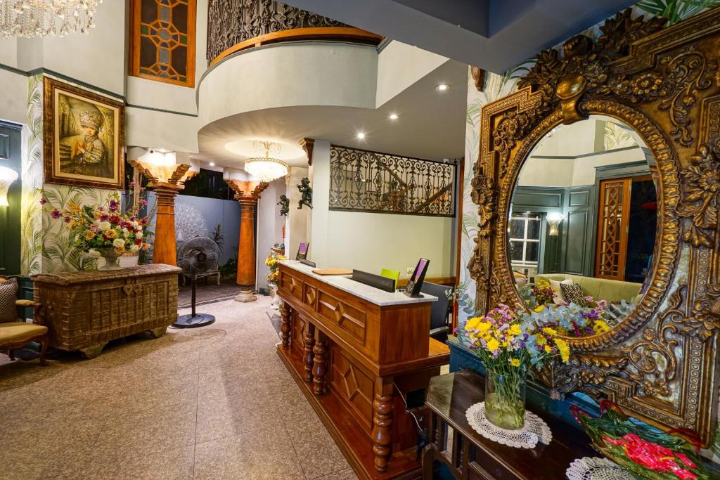 An ornate lobby reception area centered on a wooden desk and oversized gilded mirror.