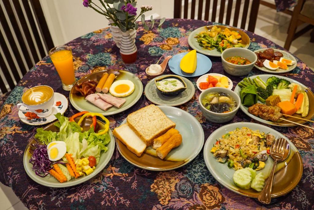 A generously set breakfast table with toast, eggs, rice, vegetables, fruit and drinks.