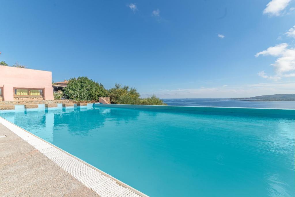 een groot blauw zwembad met uitzicht op het water bij Casa Emozione With Shared Pool - Happy Rentals in Marinella