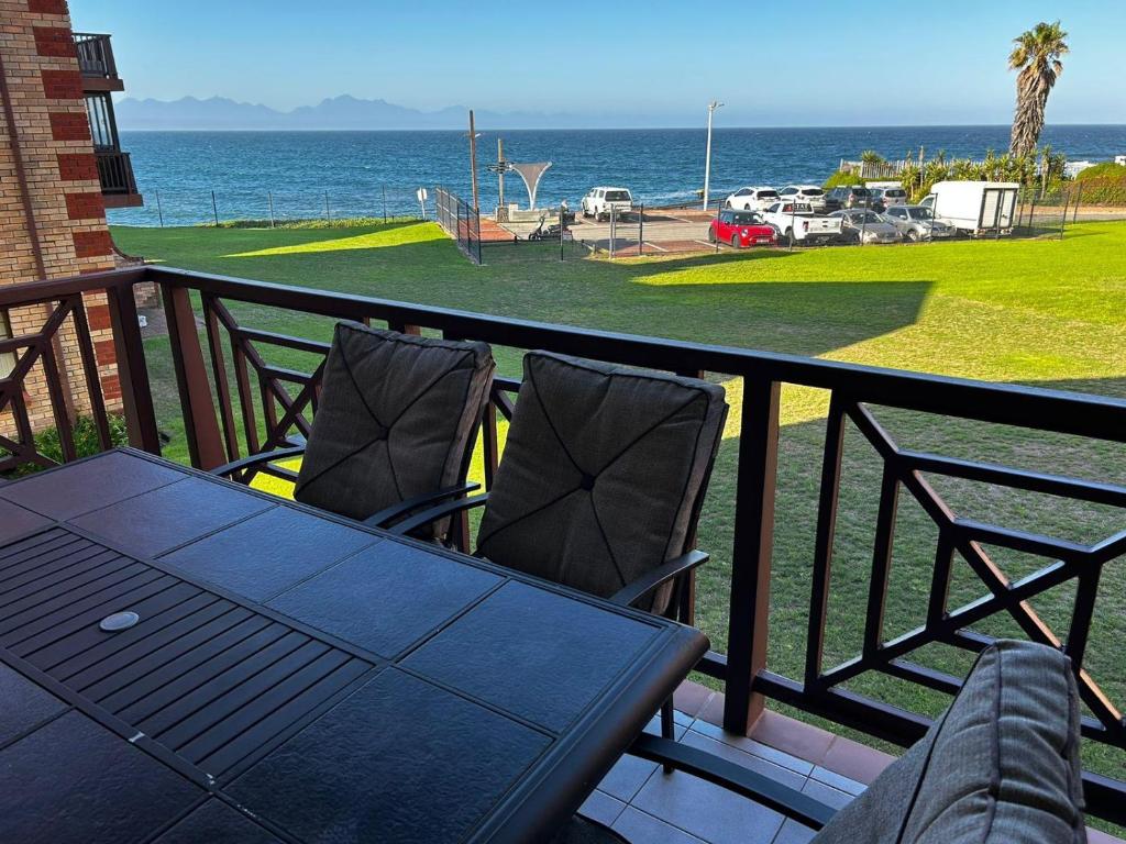 a table and chairs on a balcony overlooking the ocean at Beacon Point in Mossel Bay
