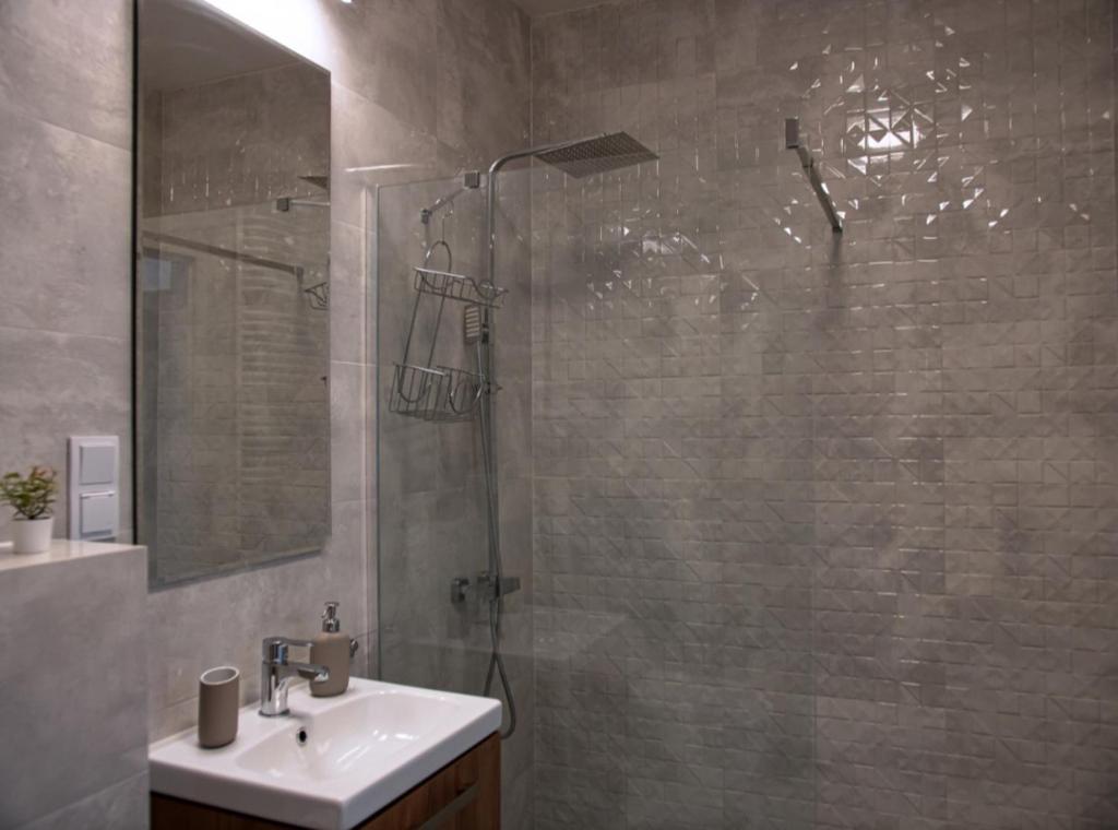 y baño con ducha y lavamanos. en Apartment Kłobucka en Varsovia