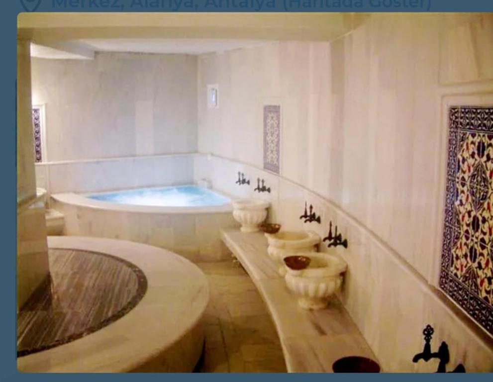 een badkamer met 3 toiletten en een bad bij VillaSun Kleopatra in Alanya