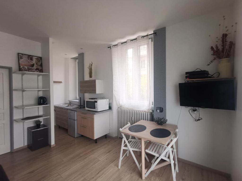 a small room with a table and a kitchen at Studio proche centre in Pontarlier