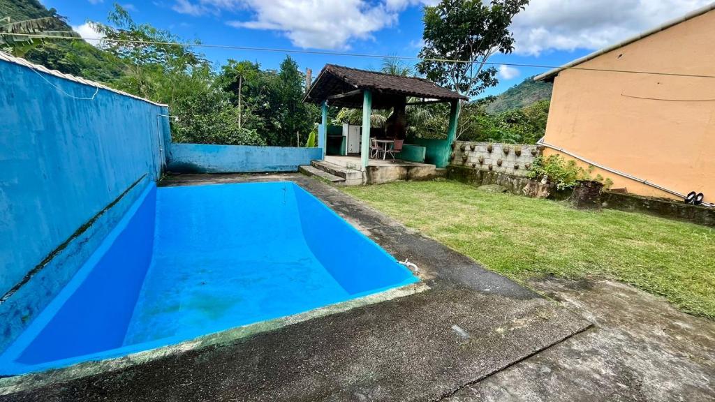 una piscina azul en un patio con cenador en Casa de temporada na Serra Macaense, en Macaé