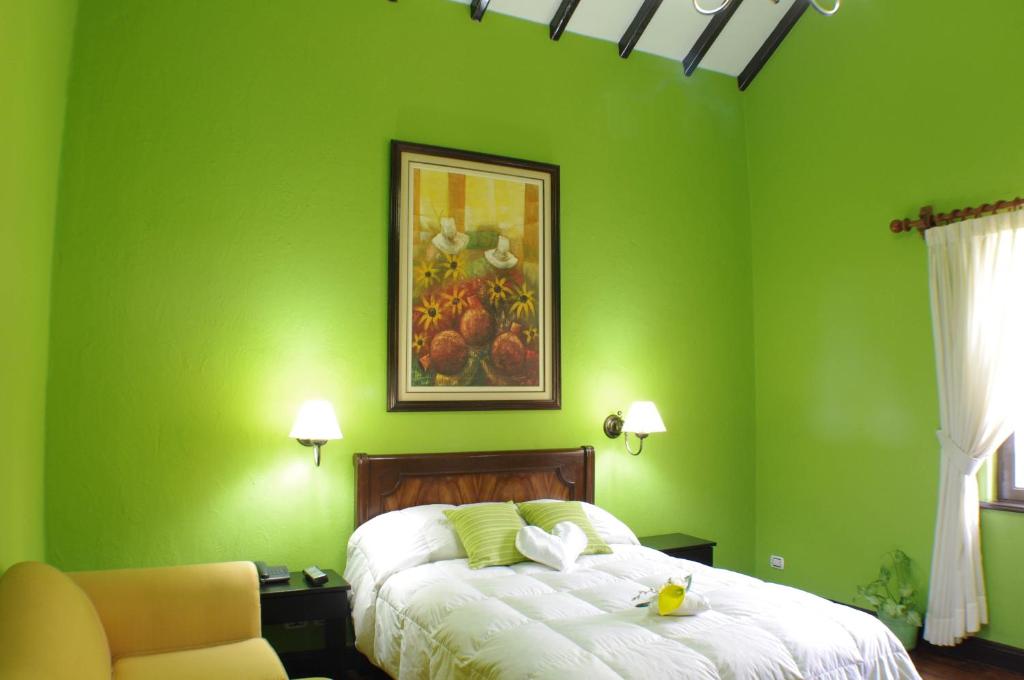 a green bedroom with a bed and a chair at La Posada De Los Cóndores in Chaclacayo