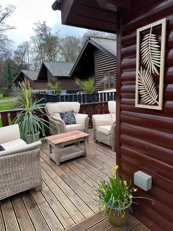 eine Holzterrasse mit Stühlen und einem Couchtisch in der Unterkunft Max's Woodland Lodge in Bridlington