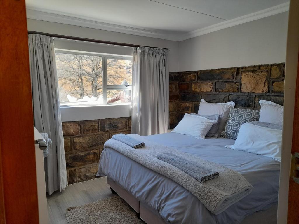a bedroom with a bed with a brick wall at Zamenkomst River Lodge in Maclear