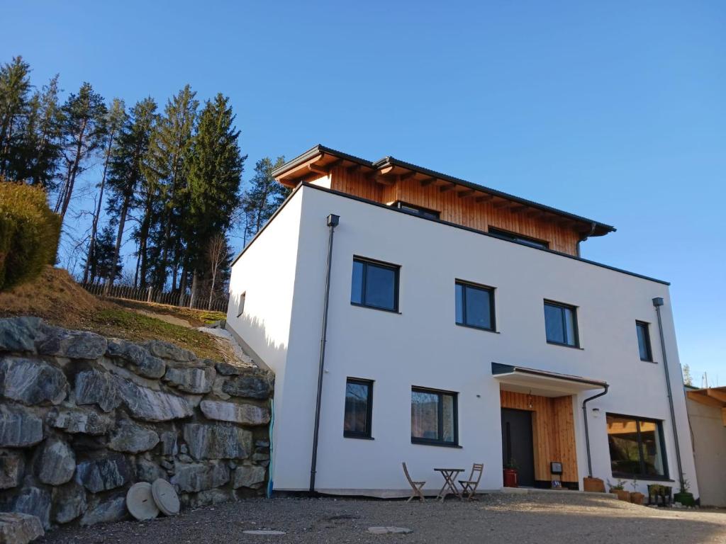a white house with a stone wall at Ferienwohnung Gerlitzenblick in Villach