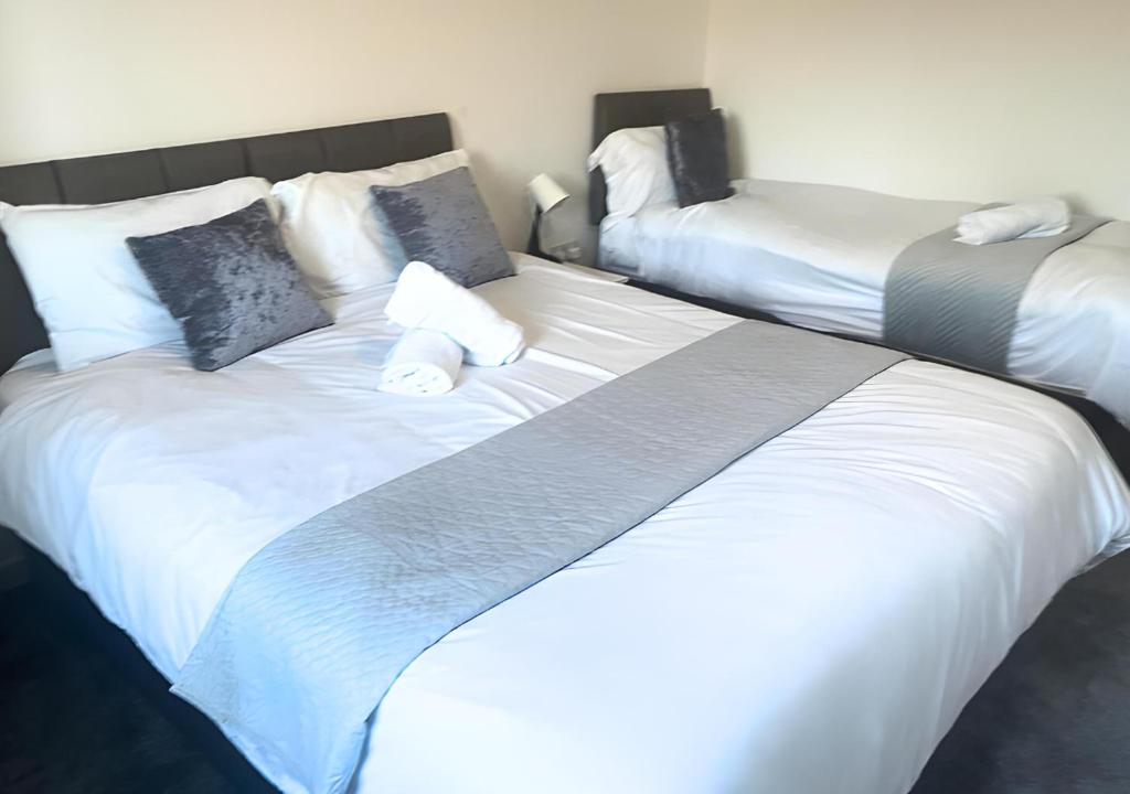 2 bedden in een slaapkamer met witte lakens en kussens bij The Dartford Lodge in Kent