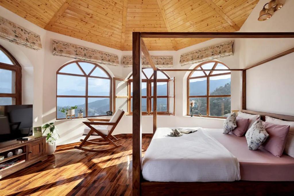 um quarto com uma cama, uma televisão e janelas em Charmed Chateau em Shimla