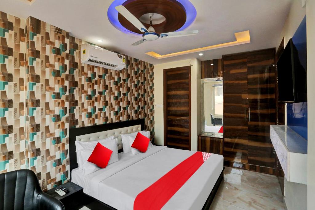 a bedroom with a bed with red pillows and a television at OYO Flagship Hotel Metro Height's near Nangloi Railway metro station in New Delhi