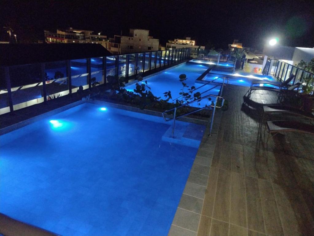 a large swimming pool at night with blue lights at Apartamento - Centro Porto de Galinhas in Escada