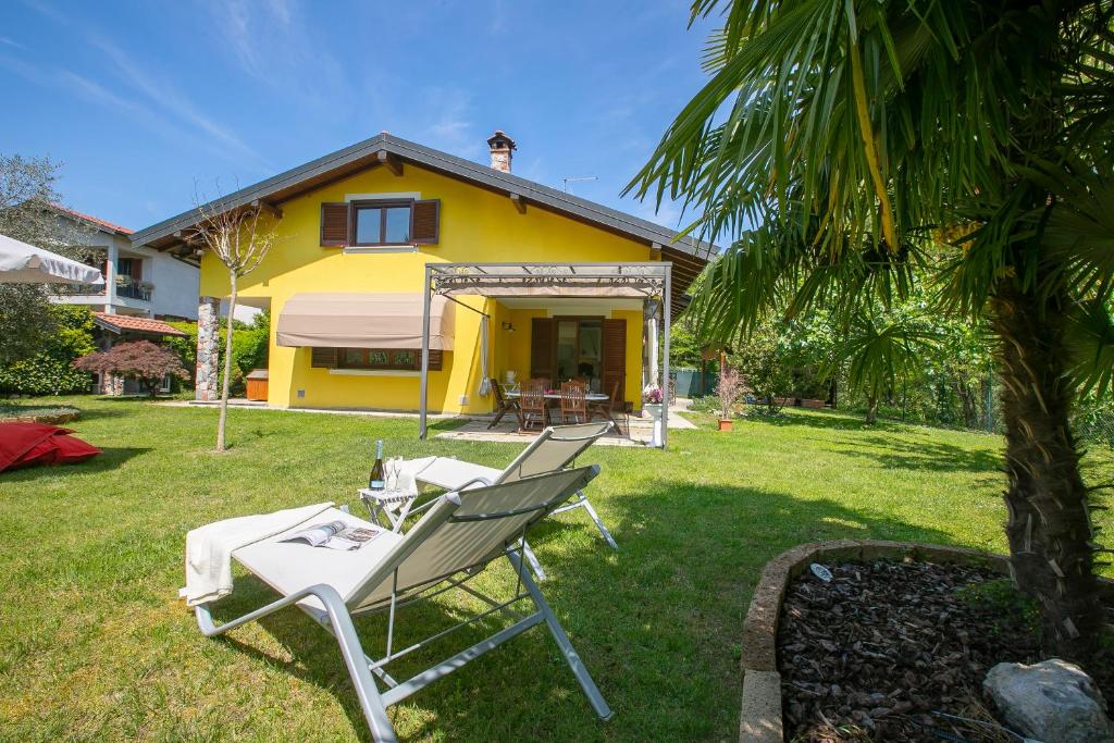 para krzeseł ogrodowych przed żółtym domem w obiekcie Villa La Dolce Vita - Happy Rentals w mieście Leggiuno