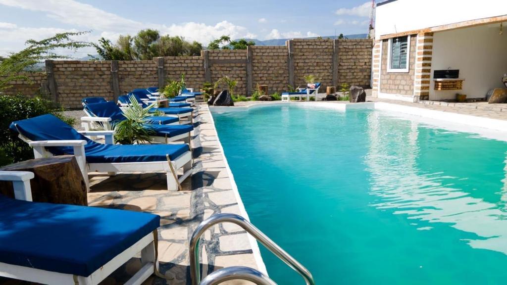 a swimming pool with blue chairs next to a building at Lakewood city Resort in Narok
