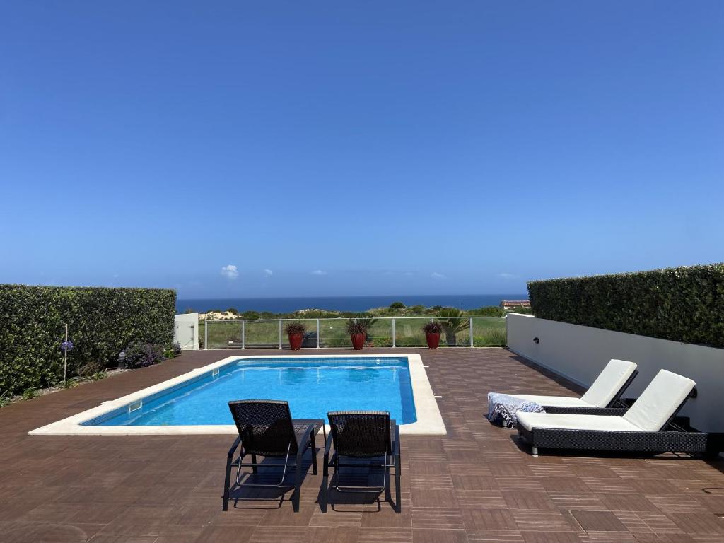 uma piscina com duas cadeiras e uma piscina em Fantástica V3 Vista Mar Golfe Praia Del Rey em Amoreira