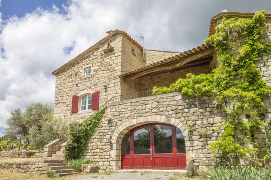 a stone house with red doors and red windows at Mas Chantequinson in Les Assions
