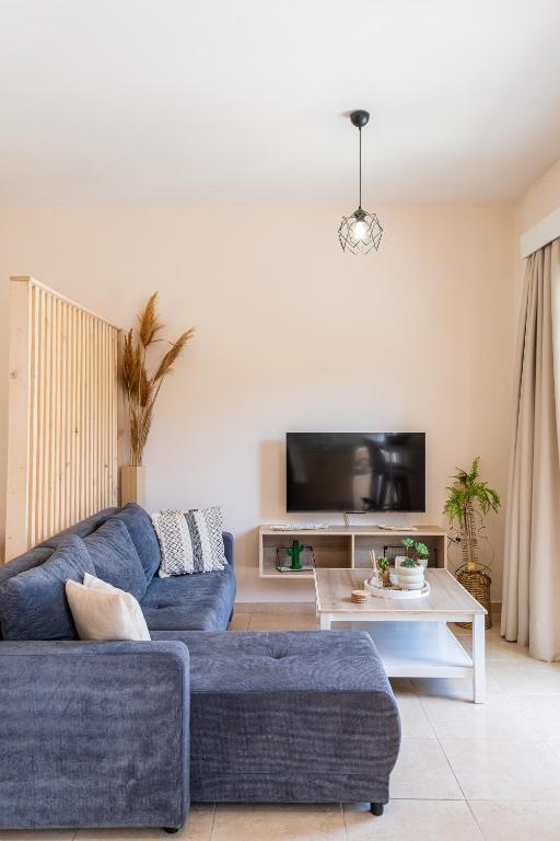 a living room with a blue couch and a tv at Casa Calida - 500m to Kos Town in Kaká Pinári