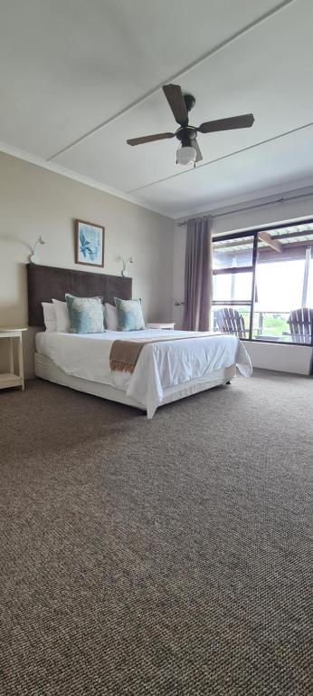 a bedroom with a large bed and a ceiling fan at Greystone Guesthouse in Jeffreys Bay