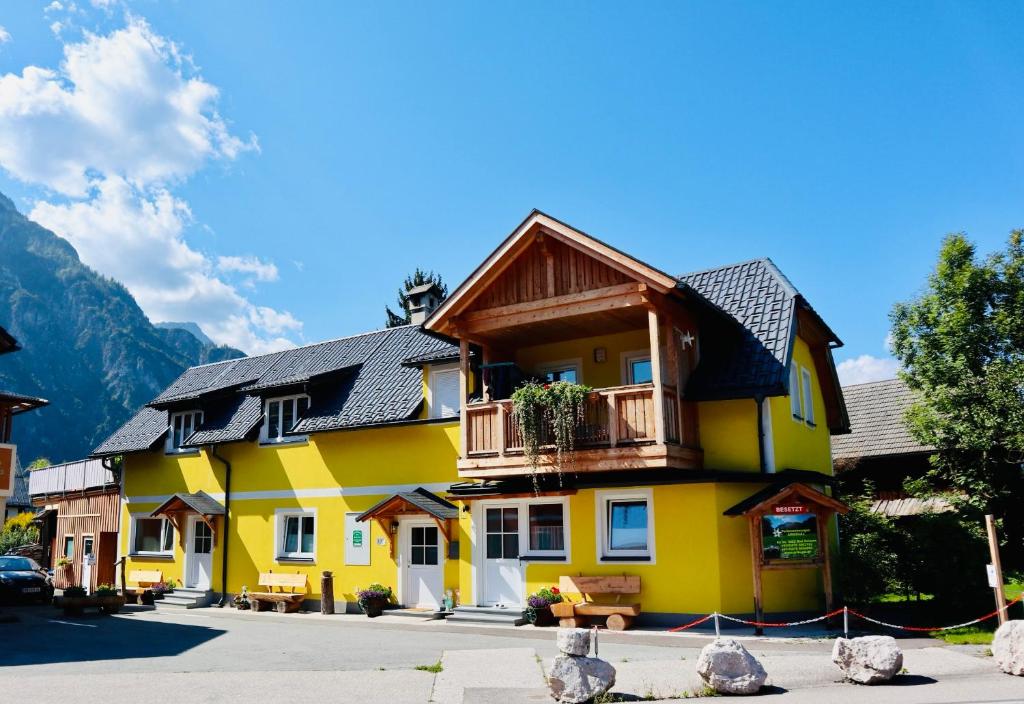 een geel huis met een houten dak bij Ferienwohnungen ARIKOGEL Bad Goisern in Bad Goisern