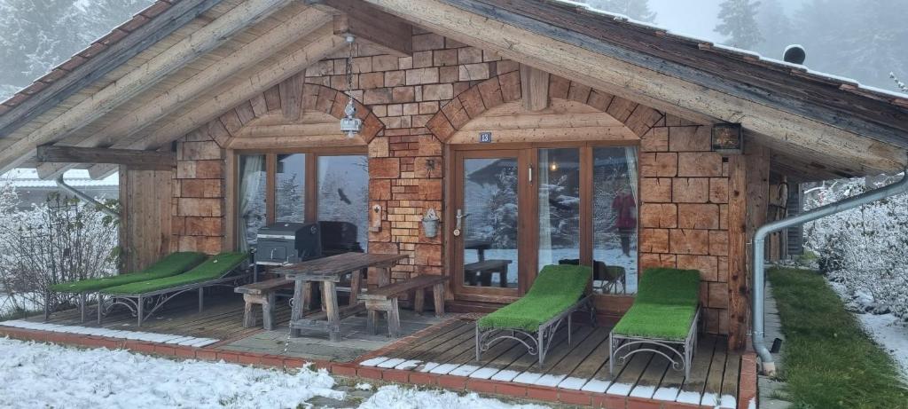 een kleine houten hut met groene stoelen en een tafel bij Casa Royal - Schönes Blockhaus mit Außensauna und Bade-Bottich in Sankt Englmar