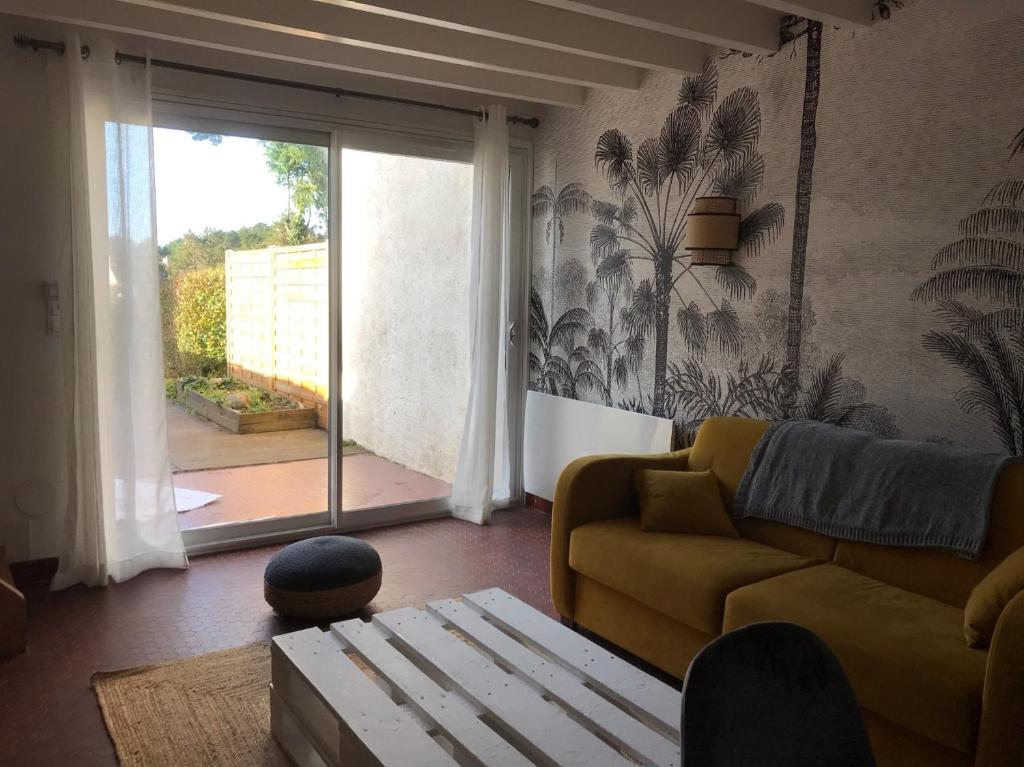 ein Wohnzimmer mit einer Couch und einer Glasschiebetür in der Unterkunft Maison Guerande La Baule in Guérande