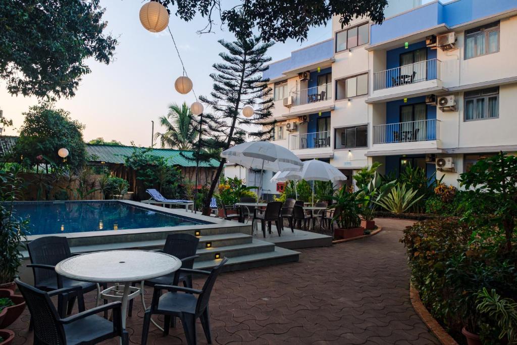 un hotel con mesas y sillas junto a una piscina en Aastha Escape Resort near Calangute Beach, en Calangute
