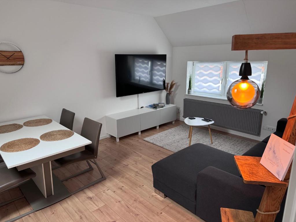 ein Wohnzimmer mit einem Tisch und einem TV in der Unterkunft Große Ferienwohnung in Ostseenähe in Schönberg