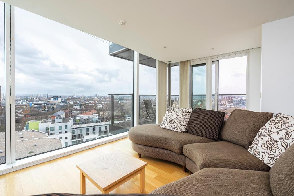 a living room with a couch and large windows at Borough Flat with City Views by UnderTheDoormat in London