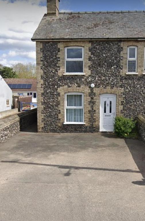 a brick house with a white door and a driveway at Charming 3 bedroom flint cottage in Lakenheath