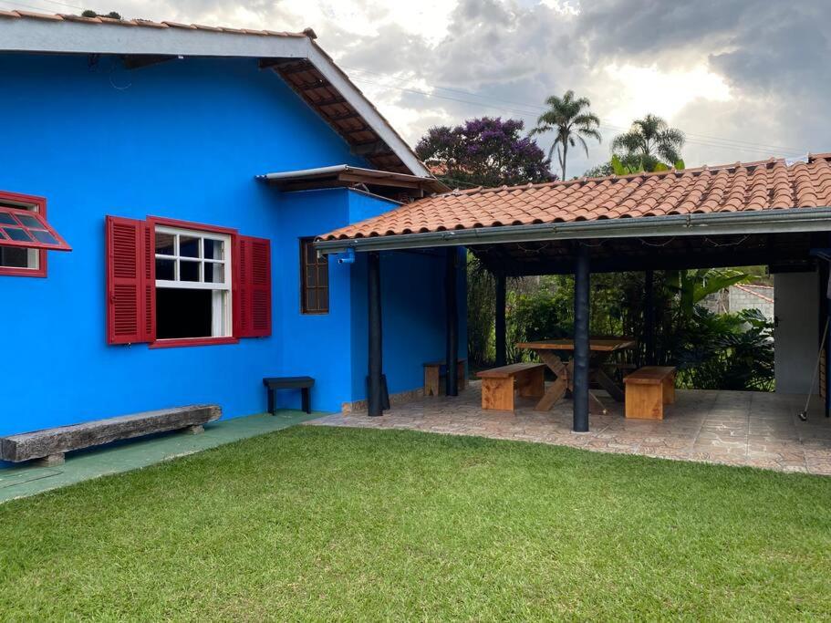ein blaues Haus mit einem roten Fenster und einem Picknicktisch in der Unterkunft Ranchinho Santa Luzia in Campos do Jordão