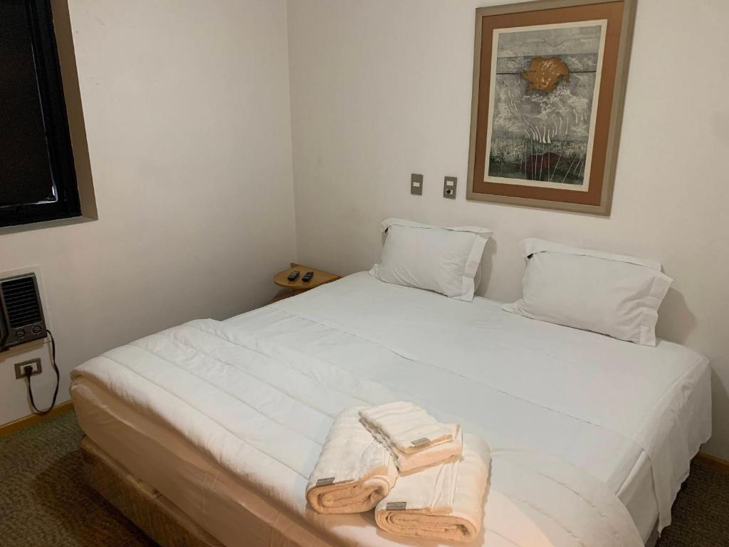 um quarto com uma cama branca com uma toalha em Get a Flat 909 - Conforto Ibirapuera em São Paulo