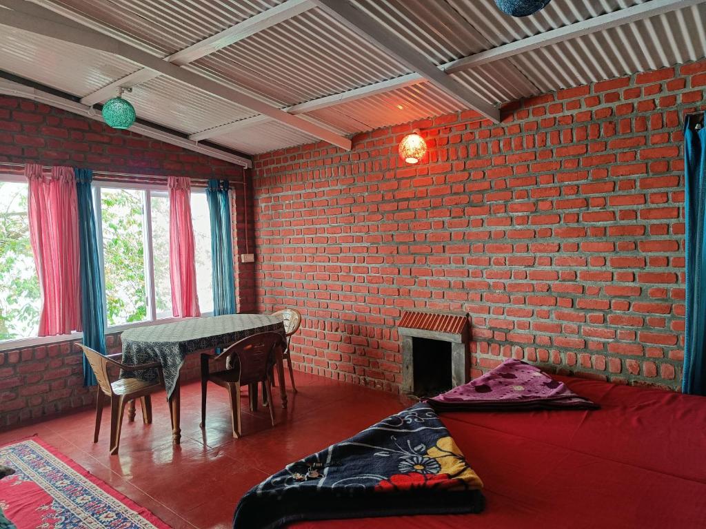 a room with a table and a brick wall at COZY HUTS in Kodaikānāl