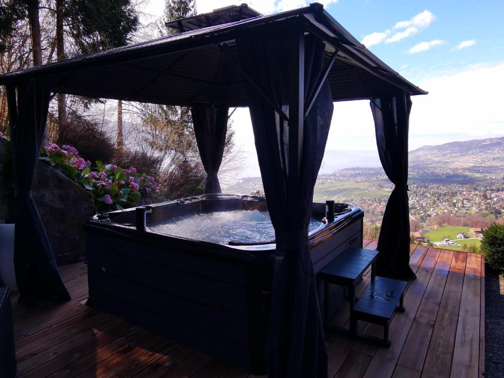 a hot tub with a canopy on a wooden deck at Elvira House Montreux, un lieu magique ! in Montreux
